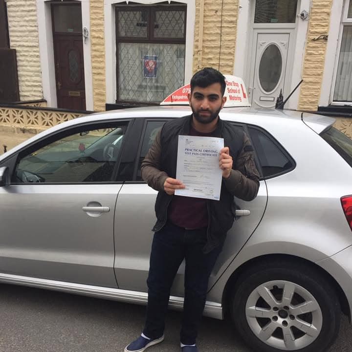 Newly passed learner holding their practical test pass certificate beside the One Stop School of Motoring car