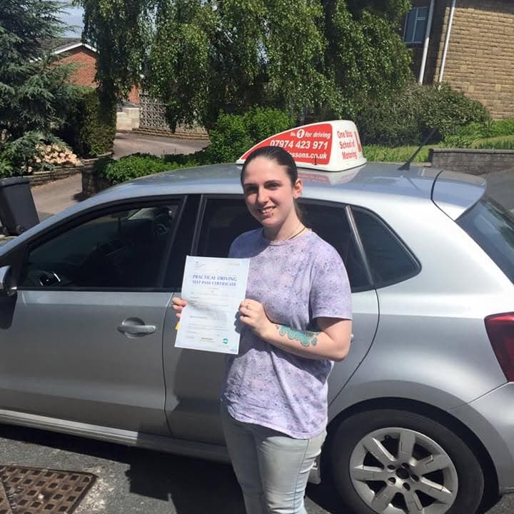 Newly passed learner holding their practical test pass certificate beside the One Stop School of Motoring car