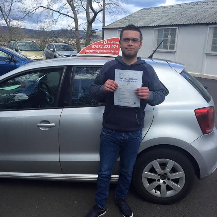Newly passed learner holding their practical test pass certificate beside the One Stop School of Motoring car
